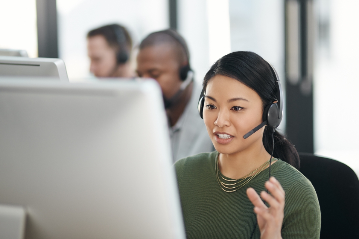 Asian female agent on a headset in front of her computer screen