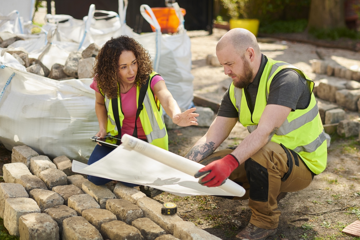 Female landscape architect reviewing blueprint with male contractor 
