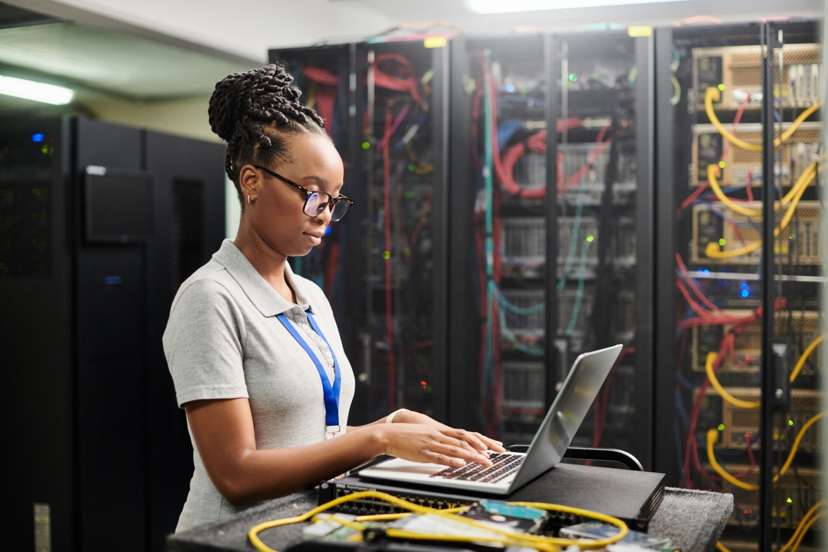 young black female working on her computer in a network server room
