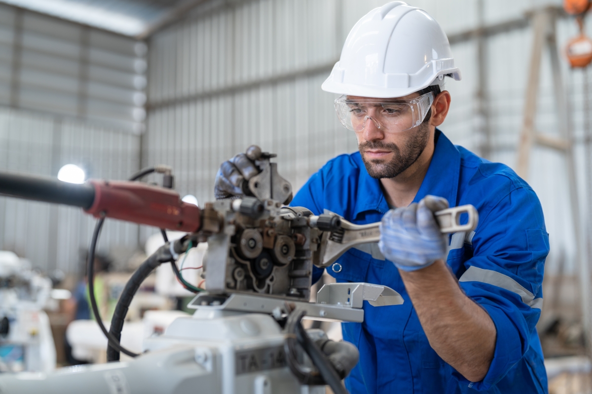 Male wearing safety gear repairing an industrial instrument