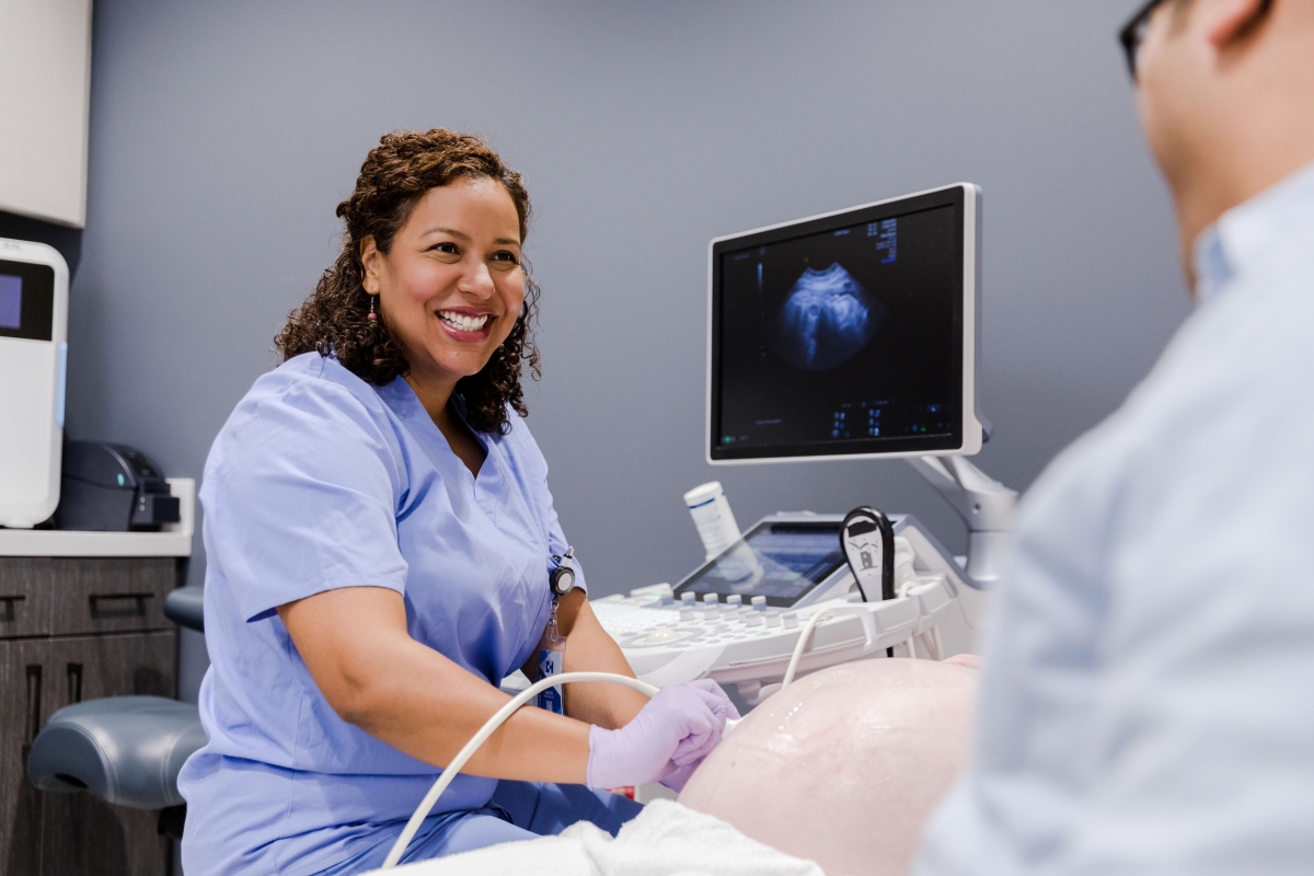 Tech smiles at dad while doing ultrasound on his wife