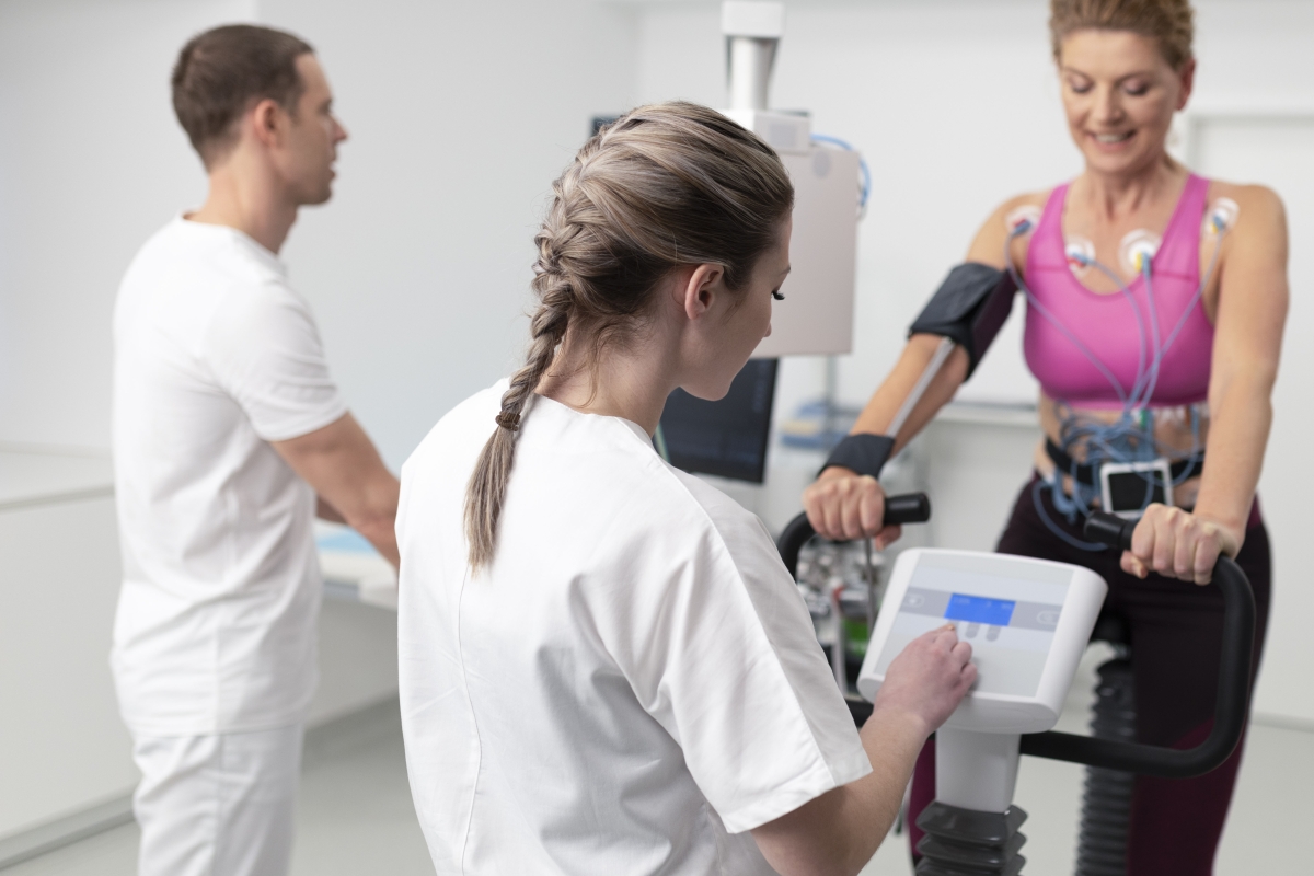 Technologists overseeing the cardiopulmonary stress test taken by a woman on a bicycle