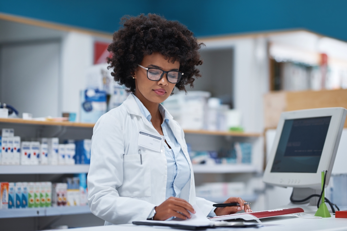 Young black female pharmacy tech recording information on a computer in a pharmacy