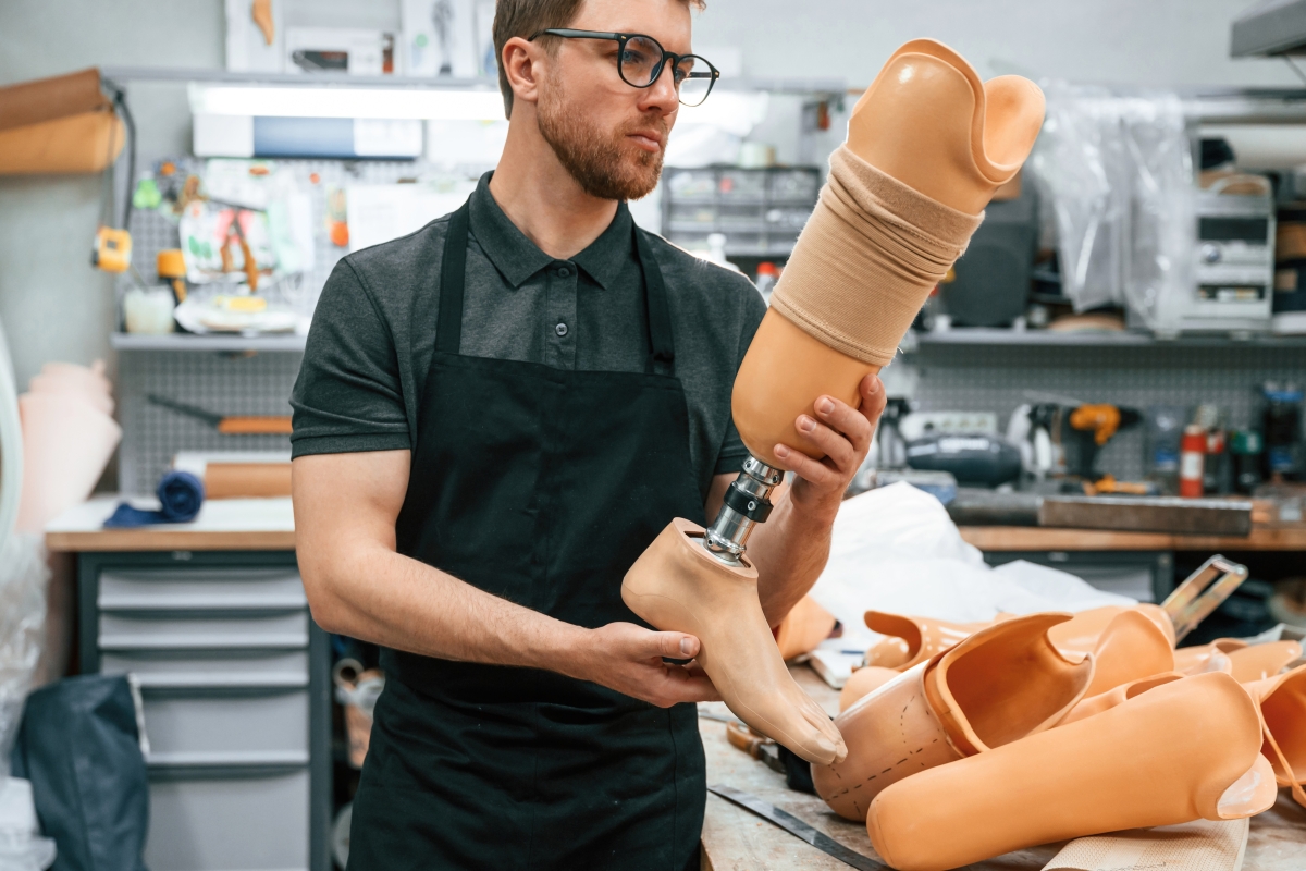 Young male technician working with prosthesis in modern laboratory 