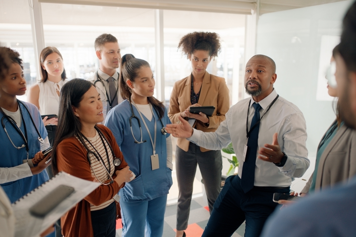 Black male manager speaking with diverse hospital staff 