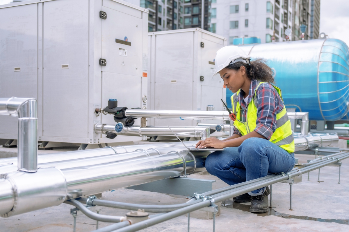 Female engineer inspects and controls the cooling system of a large factory air conditioner