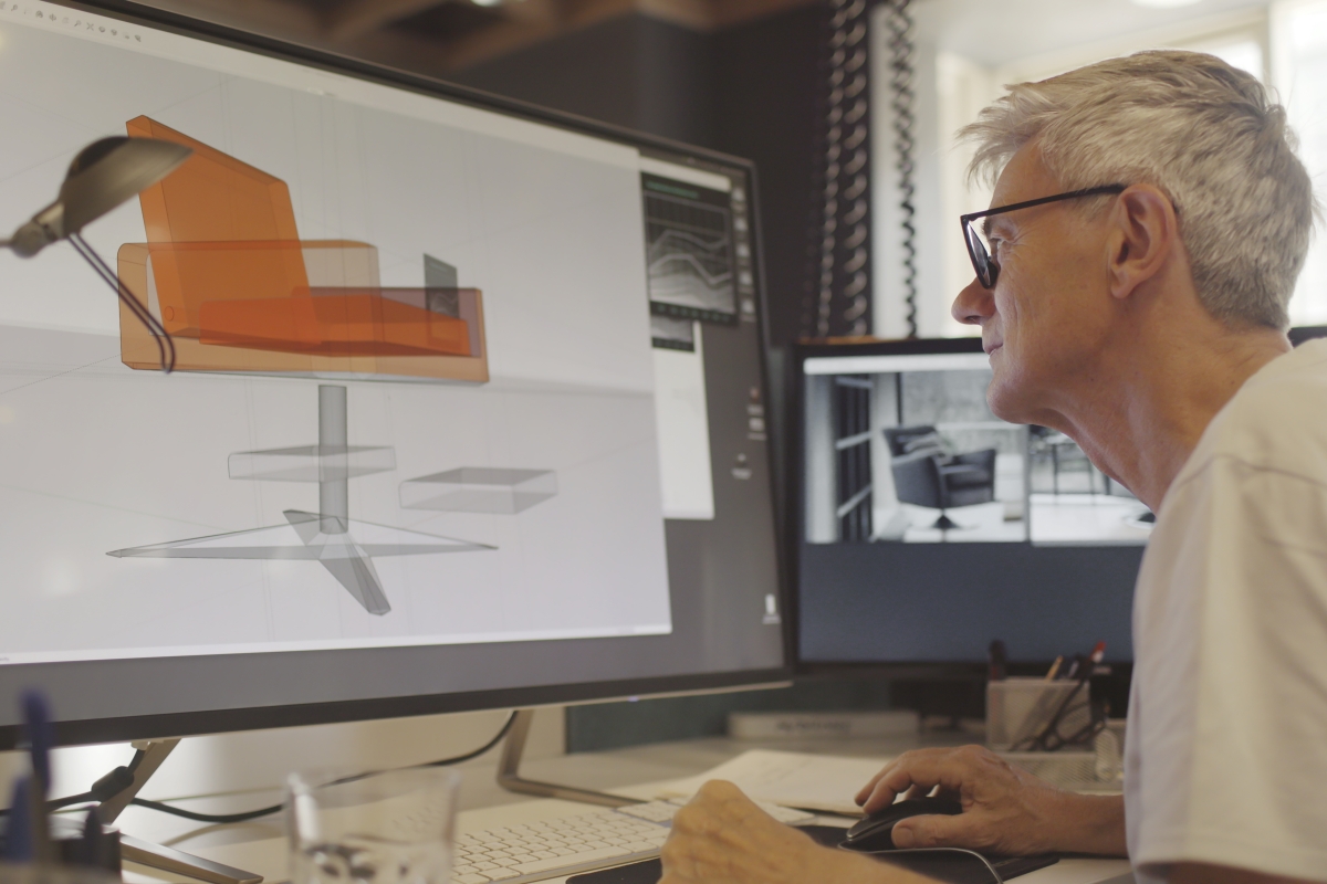 Mature male furniture designer working with CAD on his computer to design a chair..