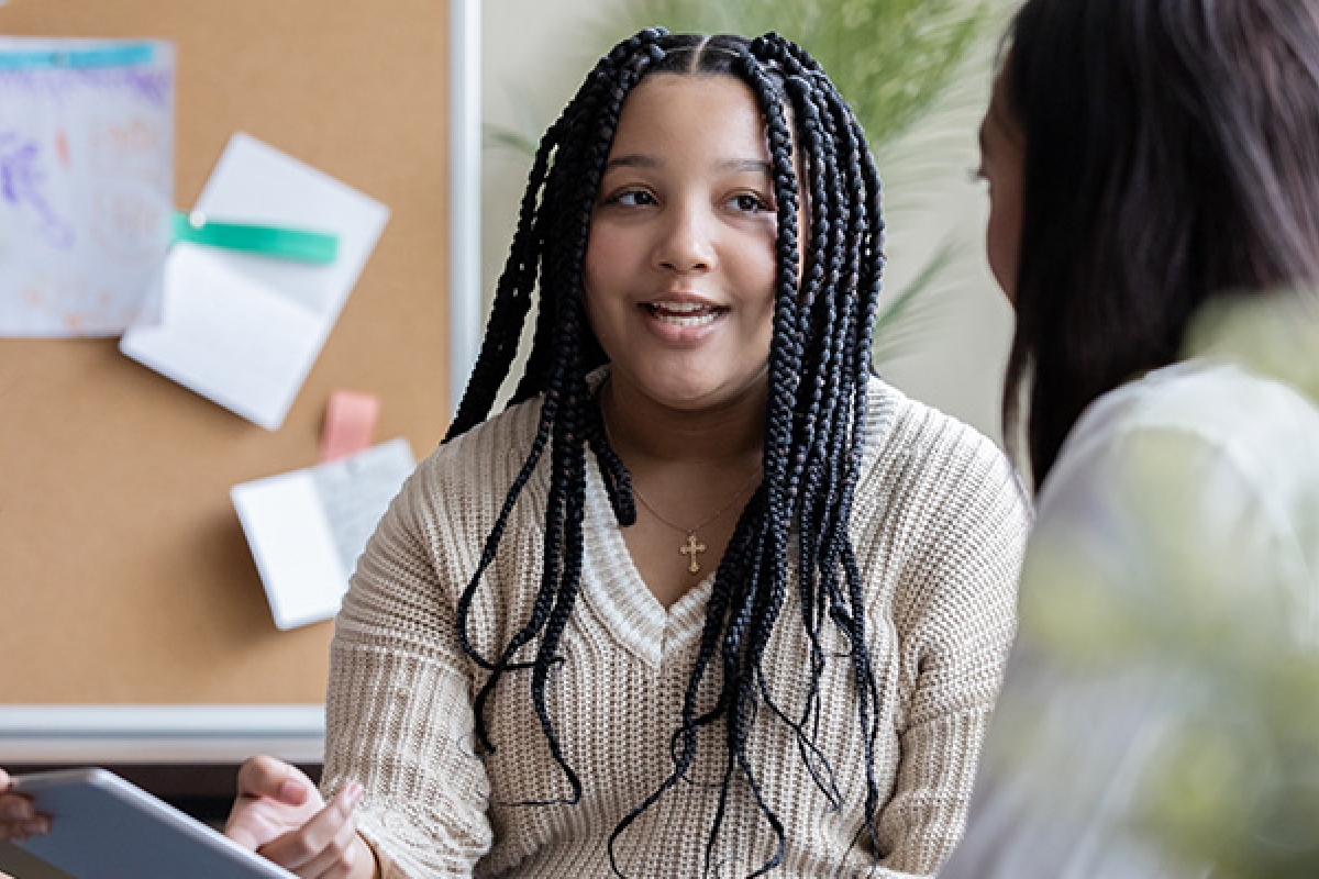 Young black female student talking with educational counsellor.