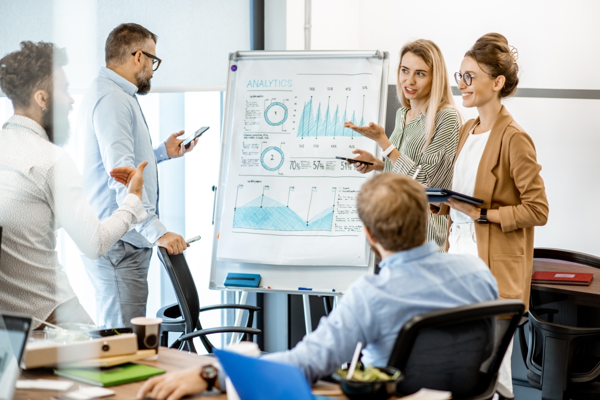 Group of diverse colleagues discussing presentation on flipchart during a meeting in the office