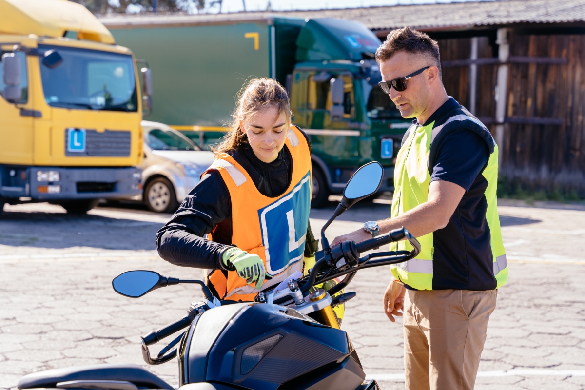 Male instructor teaching a young female student how to operate a motorcycle