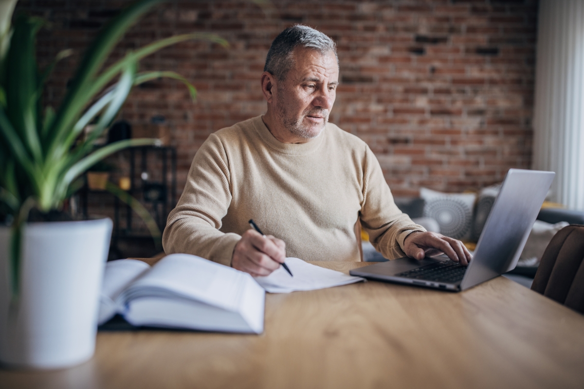 Mature male writer with book and laptop