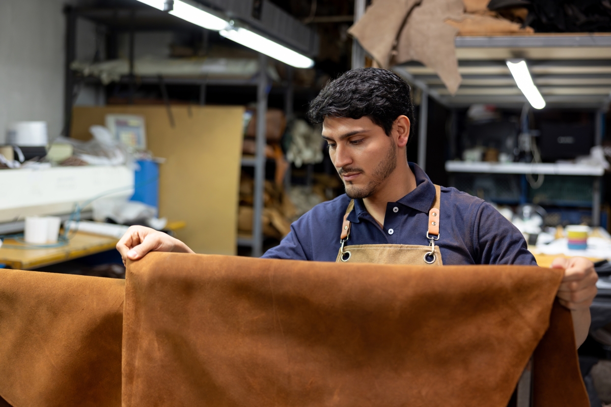 Male manufacturing worker holding piece of leather.