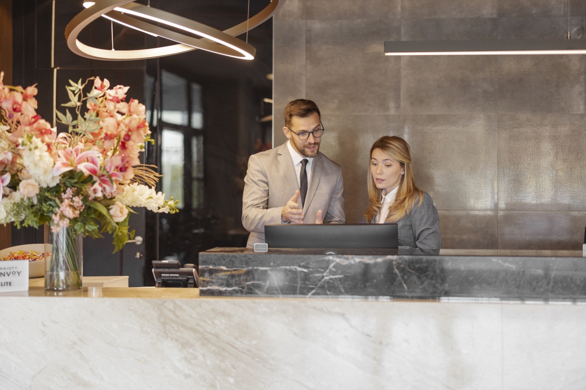 Male and female hotel receptionists working at counter