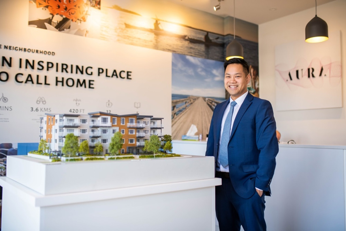 Asian male promoting a residential property using a model with signage.