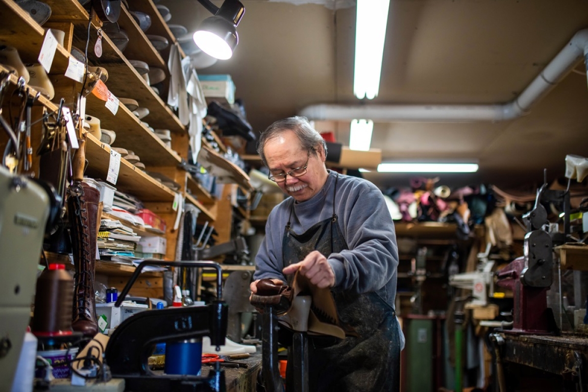 Mature Asian male repairing a shoe in his workshop.