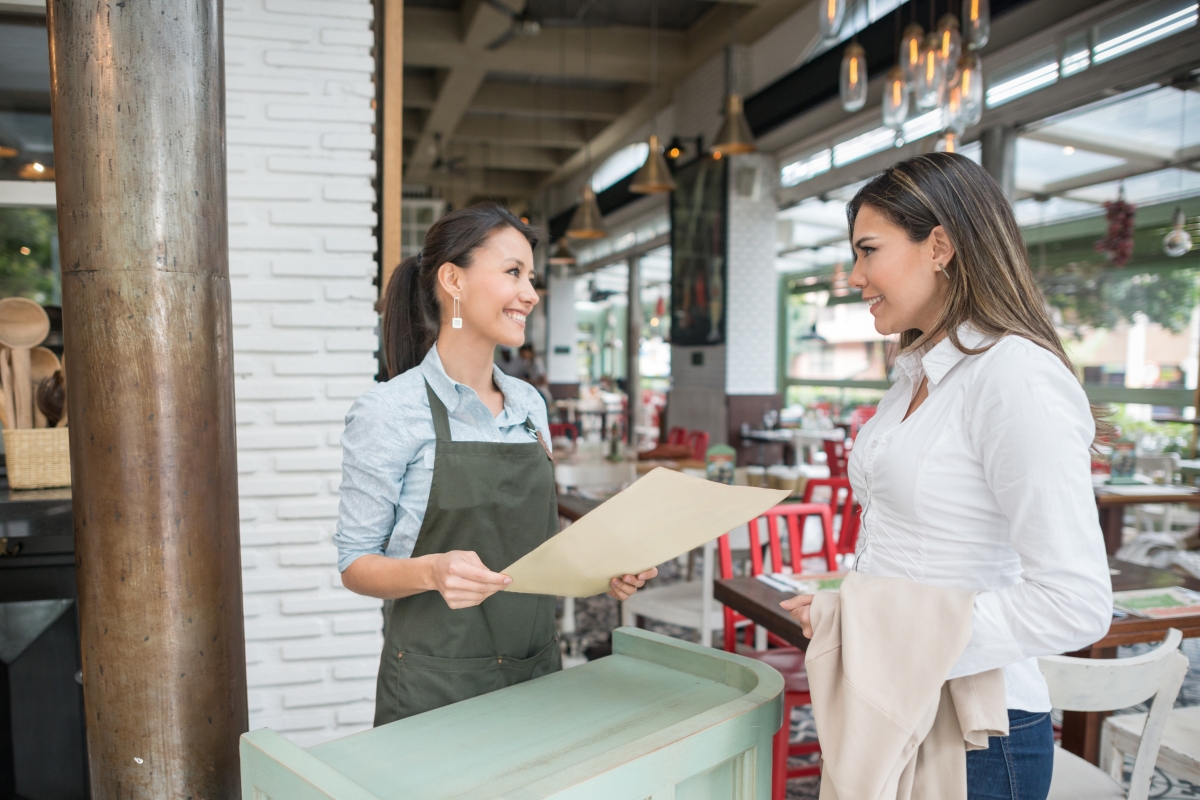 Hostess working at a restaurant and talking to client at the entrance.