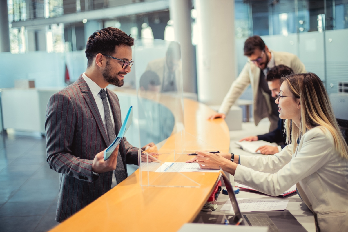 Female advisor explains to man at the bank counter the document he's about to sign.