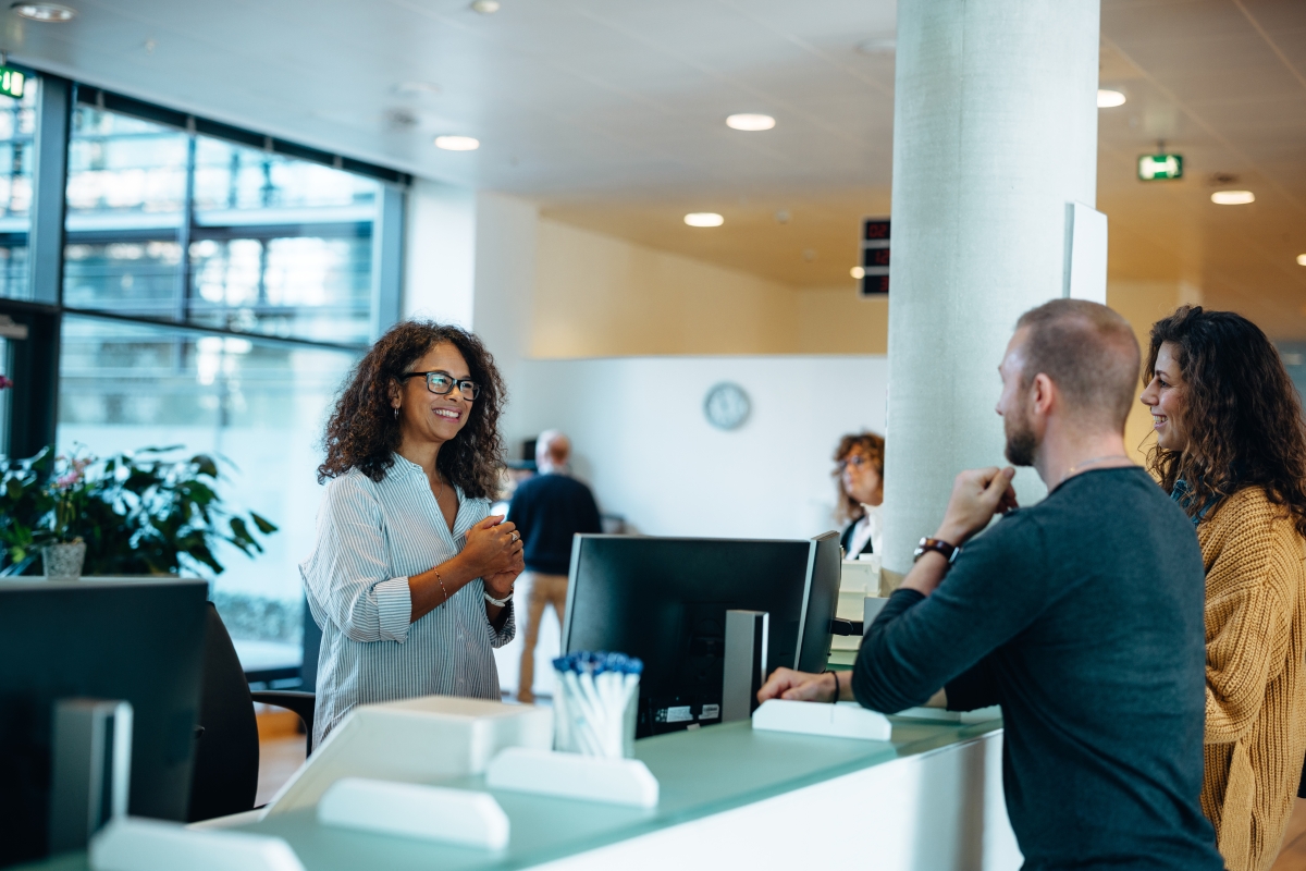 Male and female couple receiving services at a business front counter.