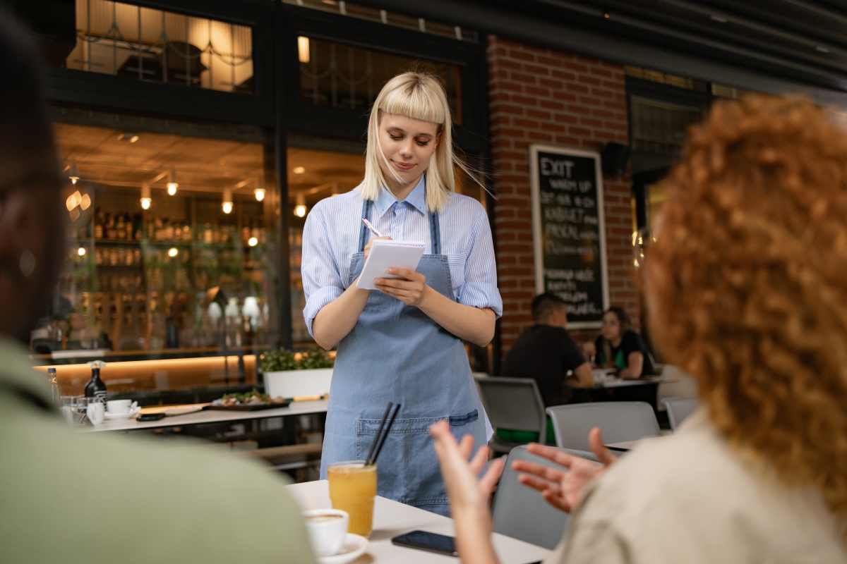 Young blond waitress writing her customers' orders in a restaurant.