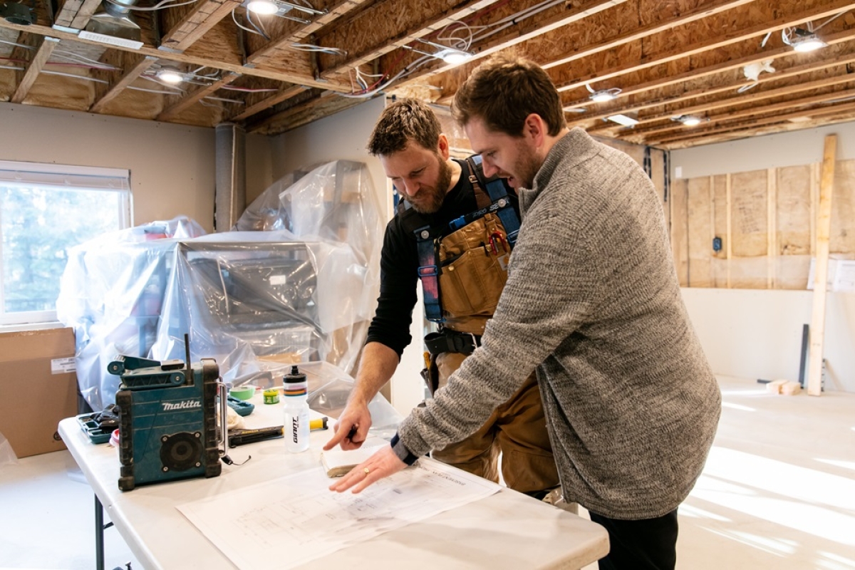 Two males discussing blueprint plans for a renovation. 