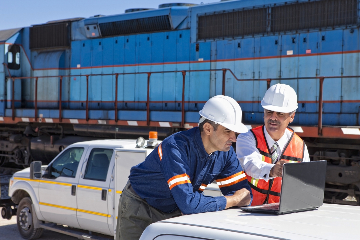 Supervisor and railway engineer discussing plans at a railroad construction site.