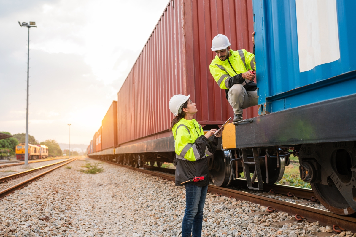 Team of railway mechanics wearing protective gear while completing safety checks.