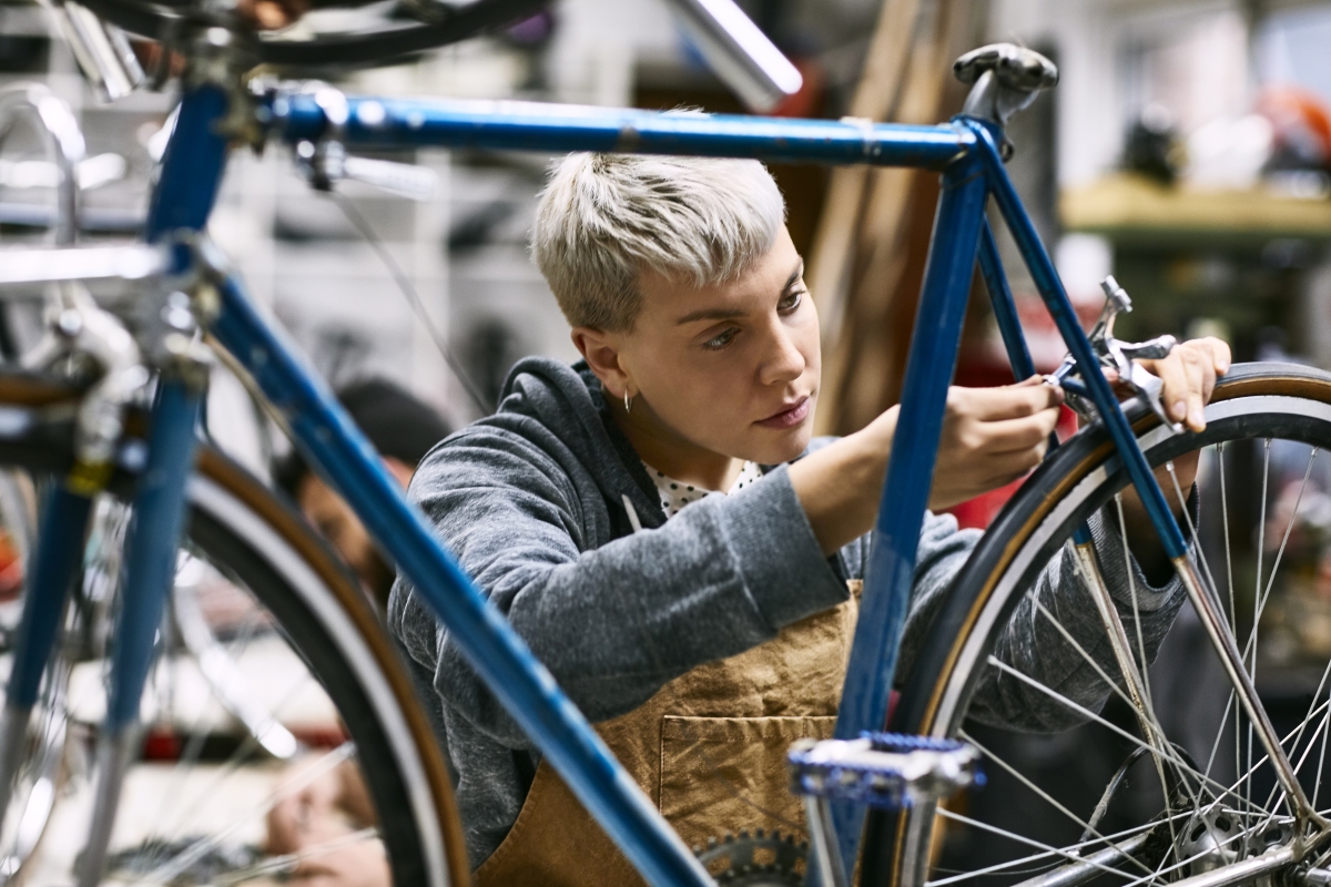 Young female employee repairing bicycle brake.