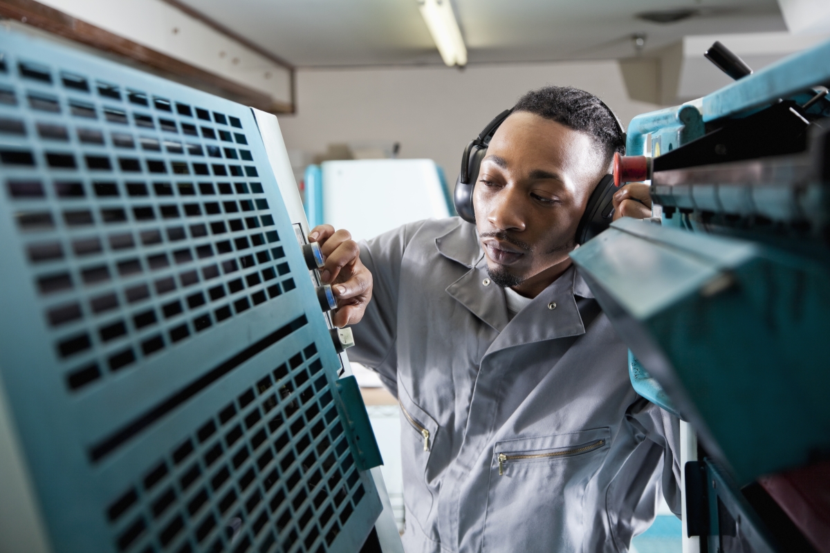 Young black male operating printing press.