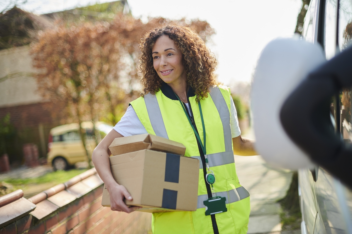 Female courier wearing a safety vest delivering parcels.