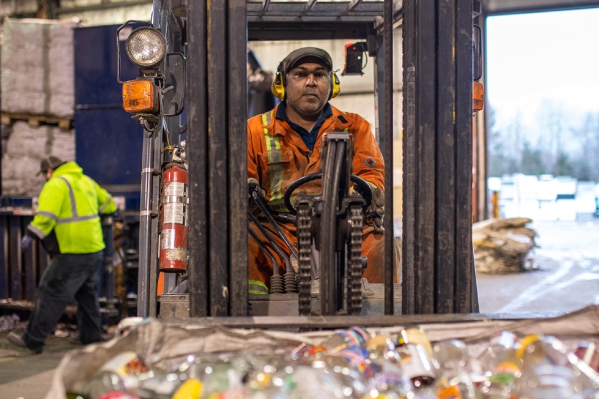 Mature male driving forklift at a recycling centre.
