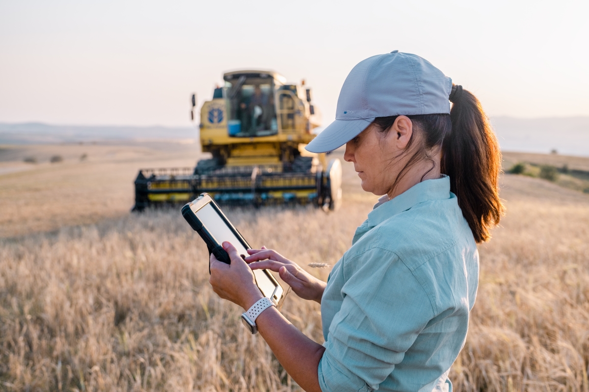 Female farmer is holding a digital tablet in a farm field.
