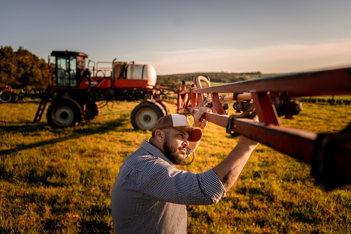 Male farmer checking agricultural machinery parts.