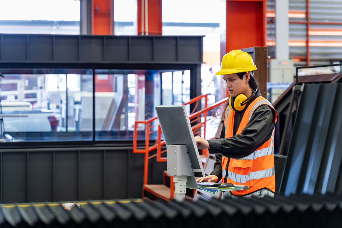 Young male operator is using touch screen computer to operate machine for production.