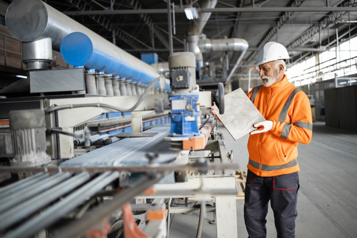 Mature male tile inspector holding tile checking color, texture and quality.