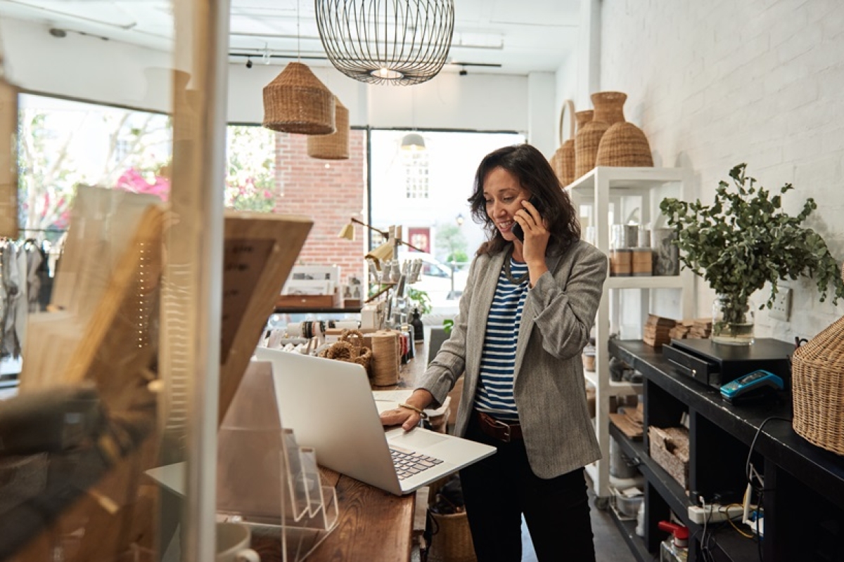 Female buyer on phone while reviewing purchase order on laptop