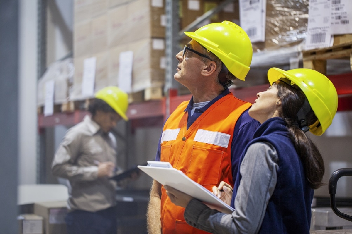 Female safety officer inspecting warehouse safety with male manager