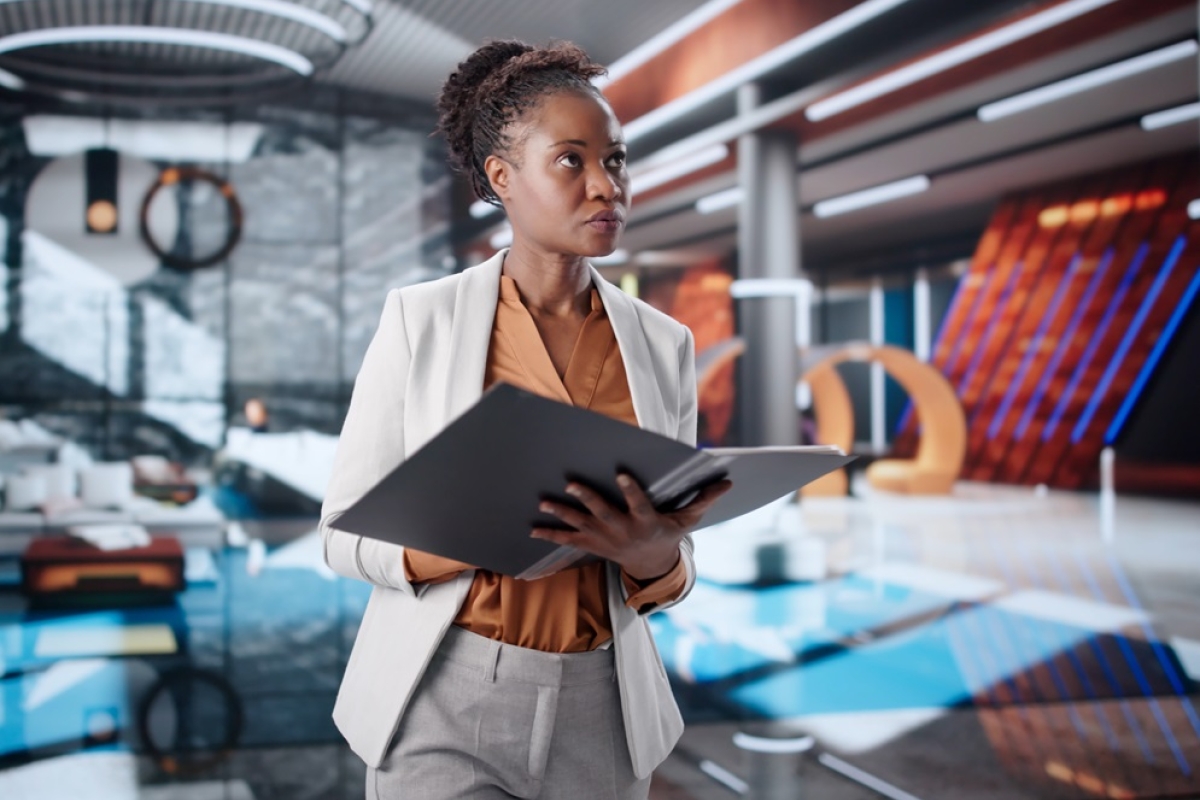 Black female hotel manager wearing white suit holding binder