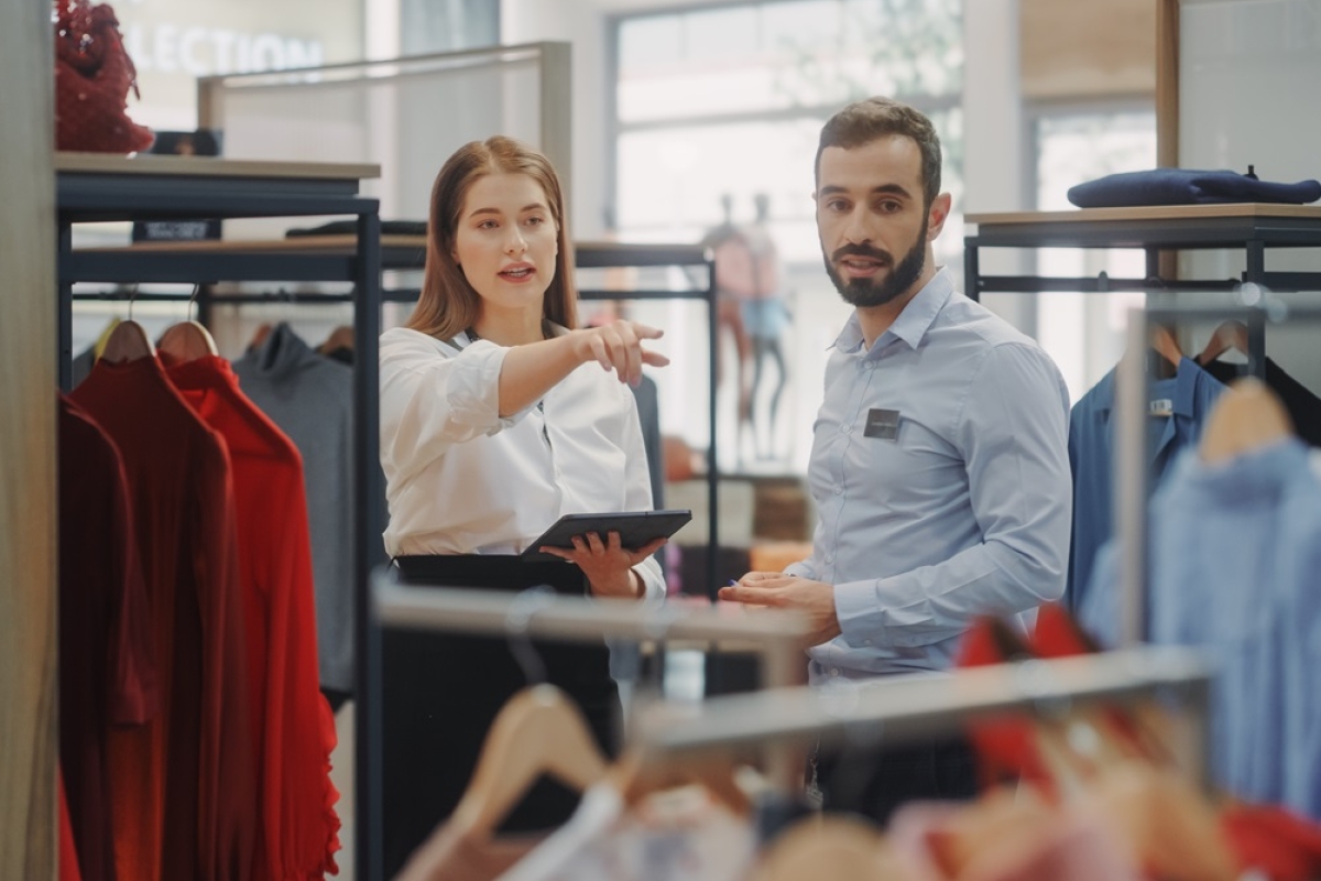 Caucasian female supervisor instructing male employee on clothing displays