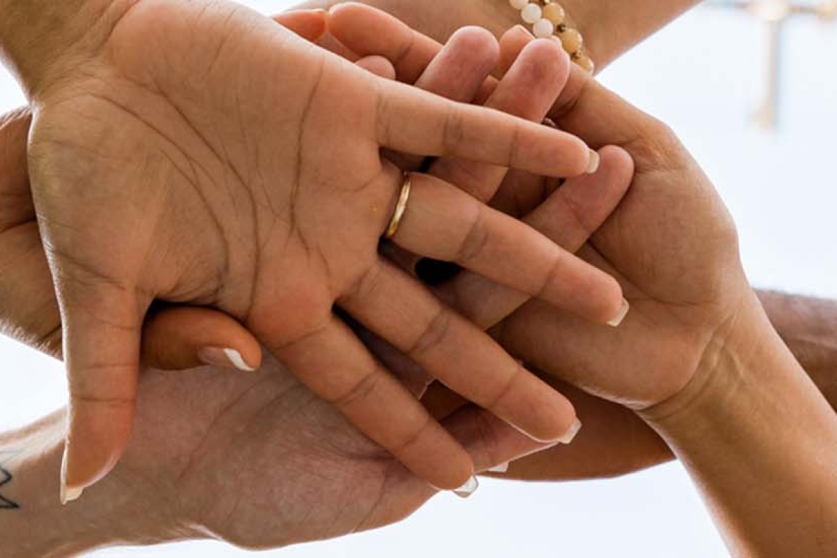 Hands with different skin tones stacked in a team cheer