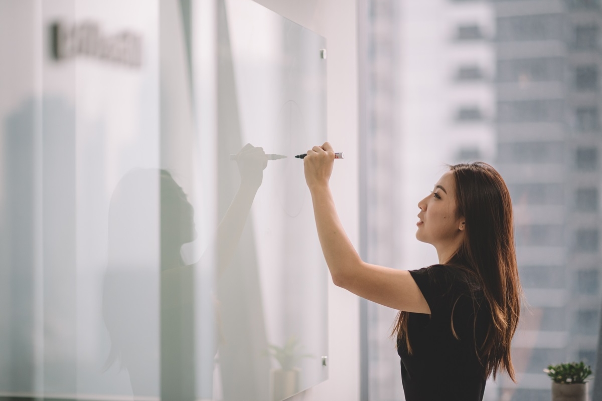 Female Asian instructor writing on a whiteboard