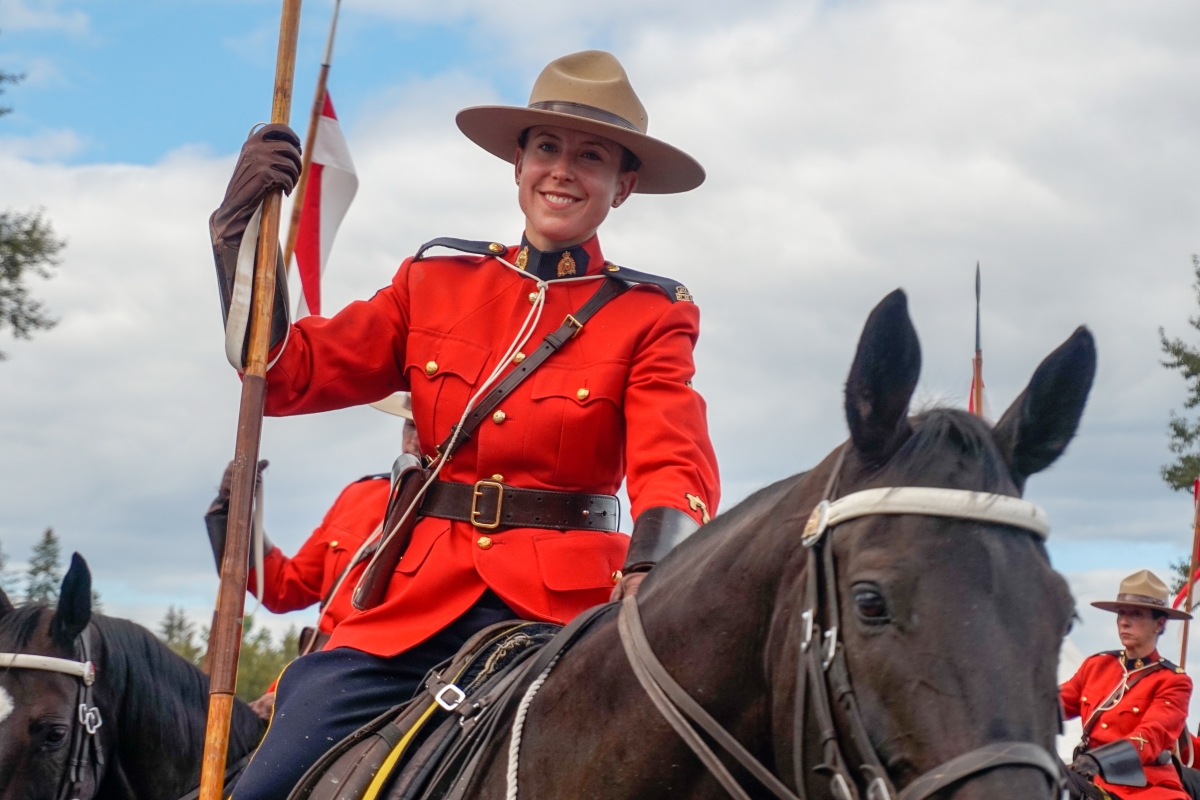 female Royal Canadian Mounted Police officer on horseback wearing the traditional red uniform and brown hat