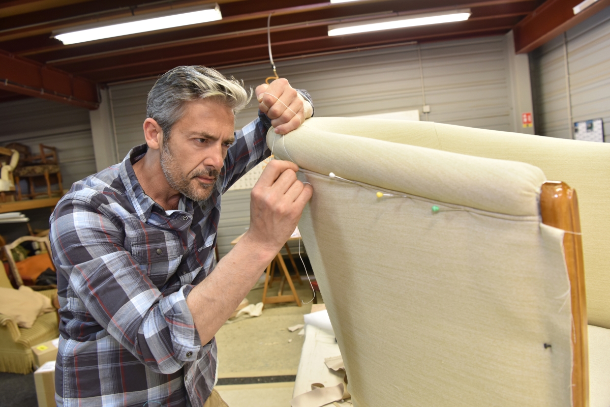 man in plaid shirt pinning fabric on a chair