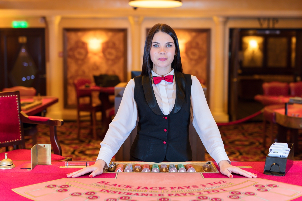 woman in uniform standing behind a blackjack table in a casino