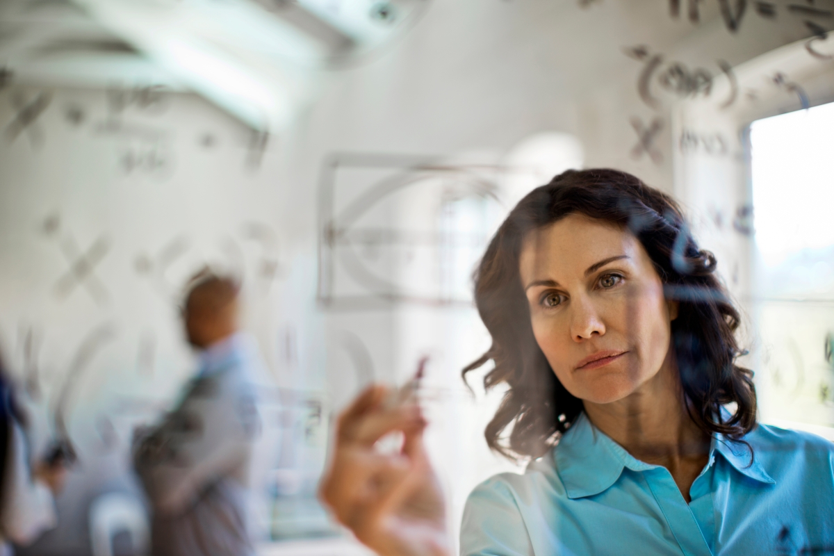person writing a mathematical equation on a board