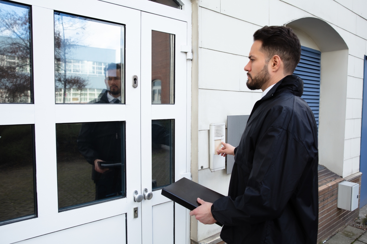 man standing outside a house ringing the doorbell