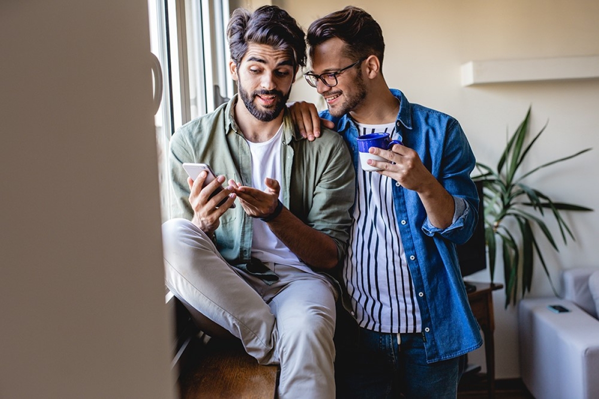 same sex male couple jobseekers checking cell phone together_1000x700_landscape_flipped