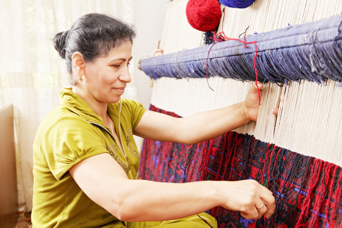 person weaving colourful fabric on a loom