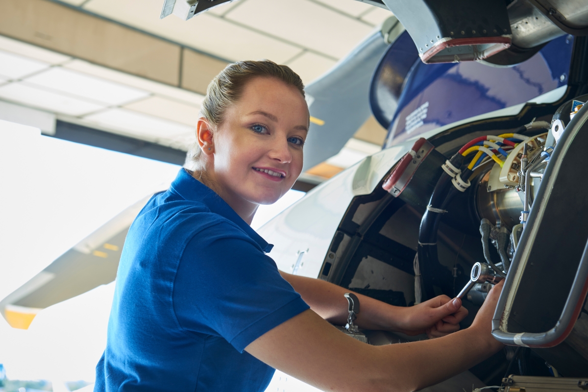 female in a blue shirt fixing small equipment with tools