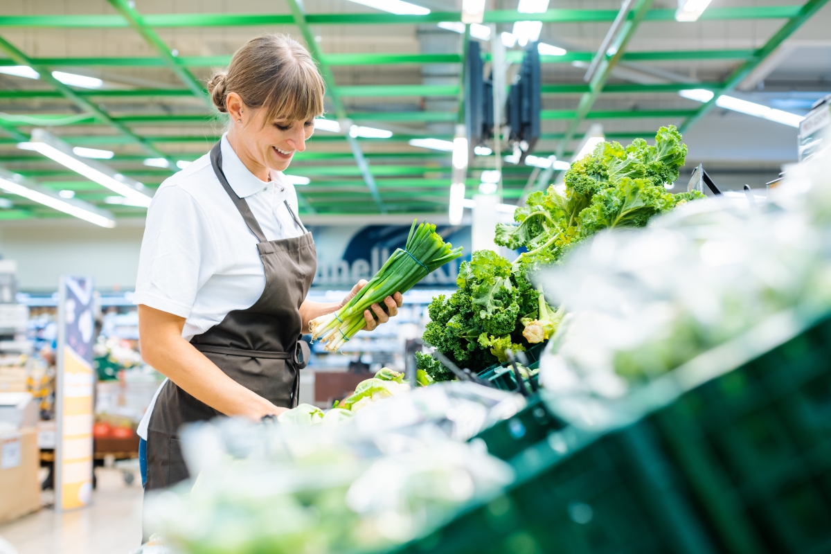 woman stocking vegetables in grocery store