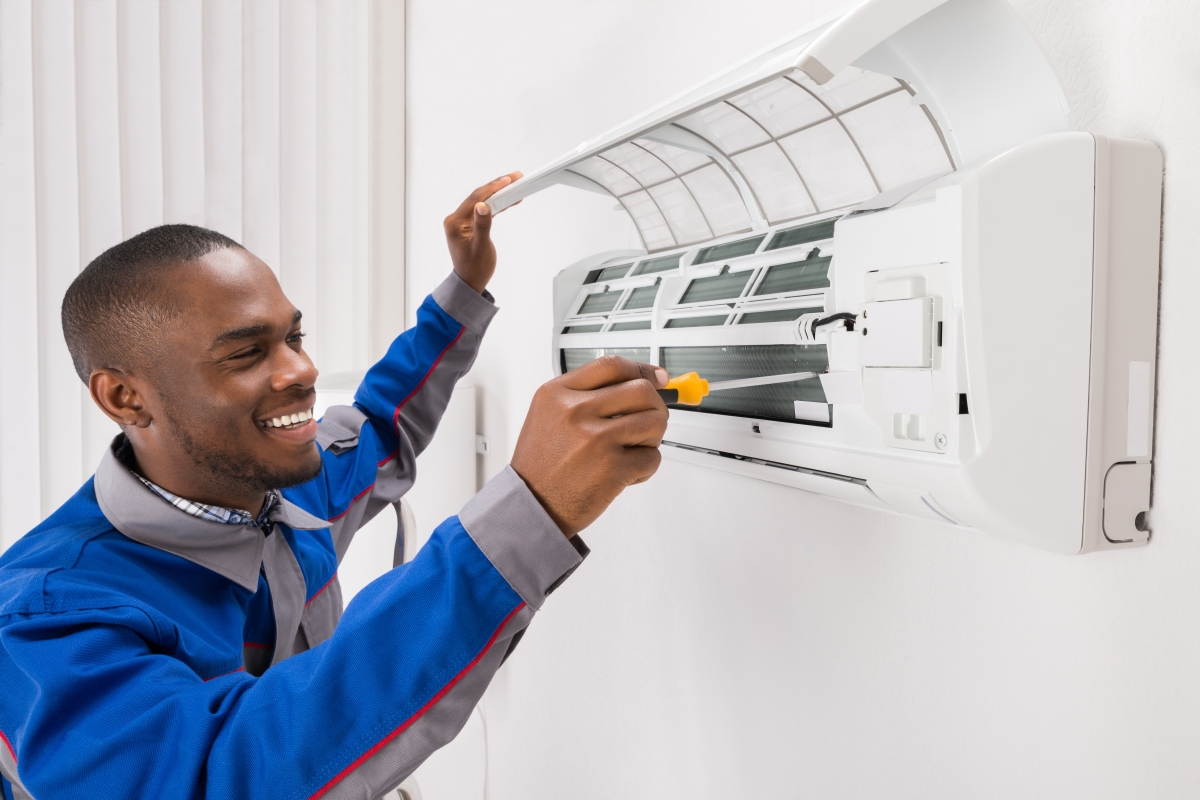man using a screwdriver to work on an air conditioner